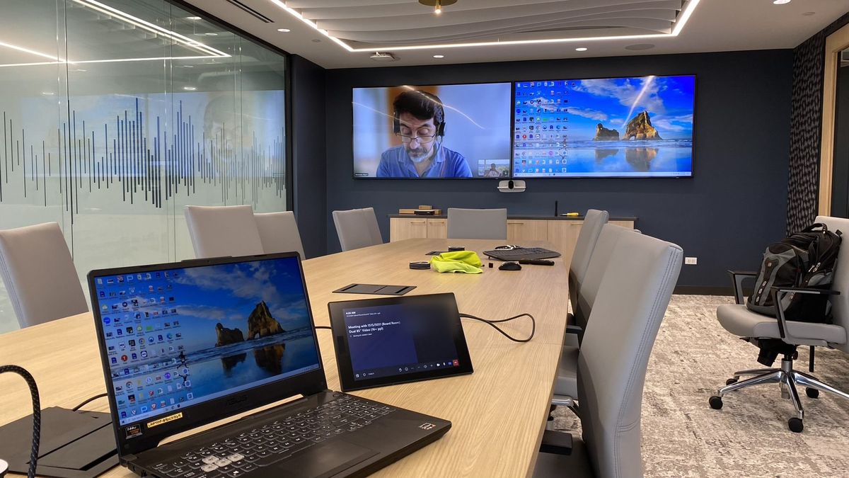 Microsoft Teams Rooms boardroom with a video call on dual displays and a tabletop touch panel, by Enlightened Audiovisual