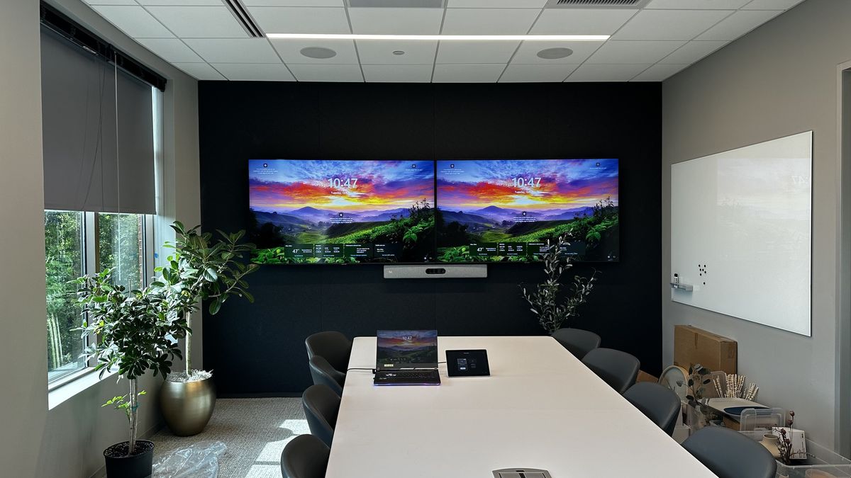 Conference room with dual displays and a video bar on a black accent wall, by Enlightened Audiovisual