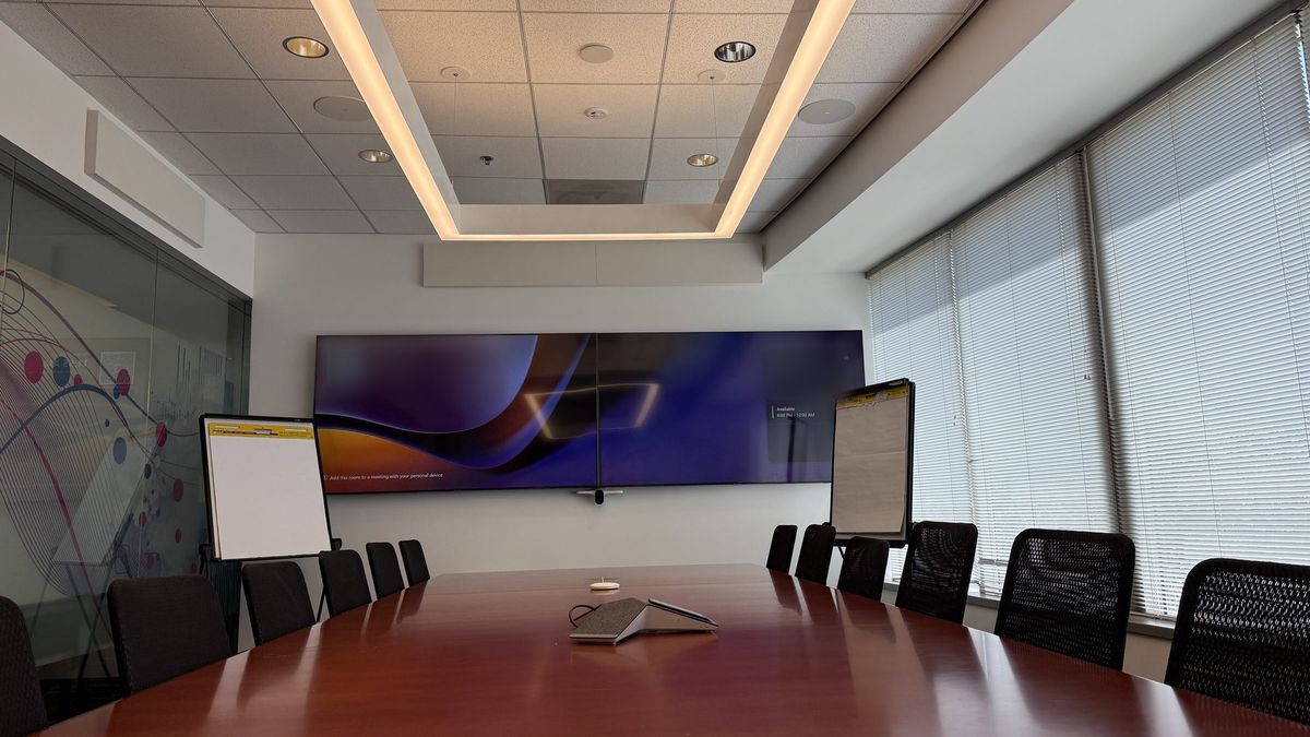Executive boardroom with an ultra-wide display, ceiling microphones, and cove lighting, by Enlightened Audiovisual