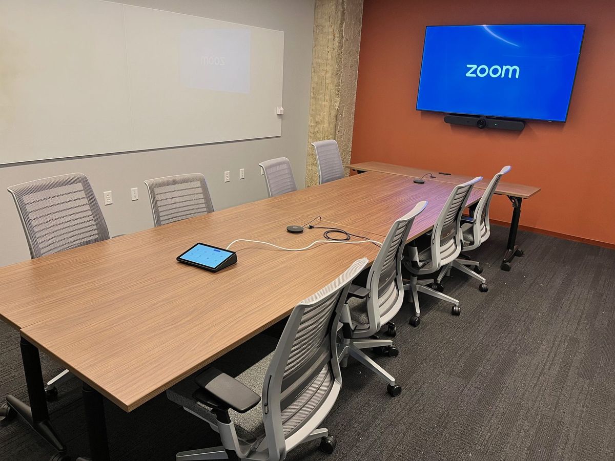 Zoom Rooms conference room with a wall display, a video bar, and a tabletop touch controller, by Enlightened Audiovisual