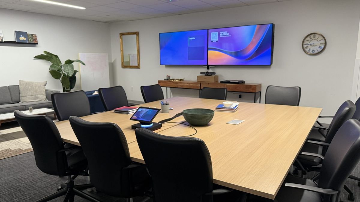 Modern meeting room with dual displays, a video bar, and a tabletop touch panel, by Enlightened Audiovisual