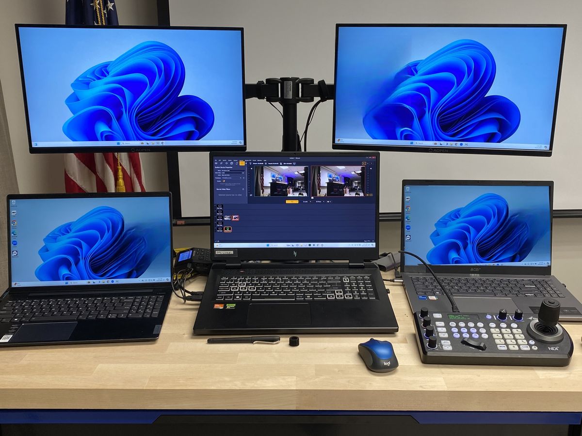 Production workstation with multiple monitors, laptops, and a PTZ camera joystick controller, set up by Enlightened Audiovisual