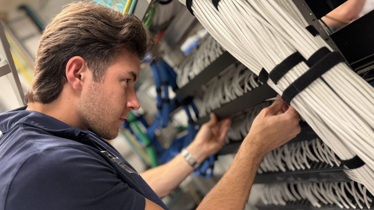 Enlightened Audiovisual technician dressing bundled network cable at an equipment rack
