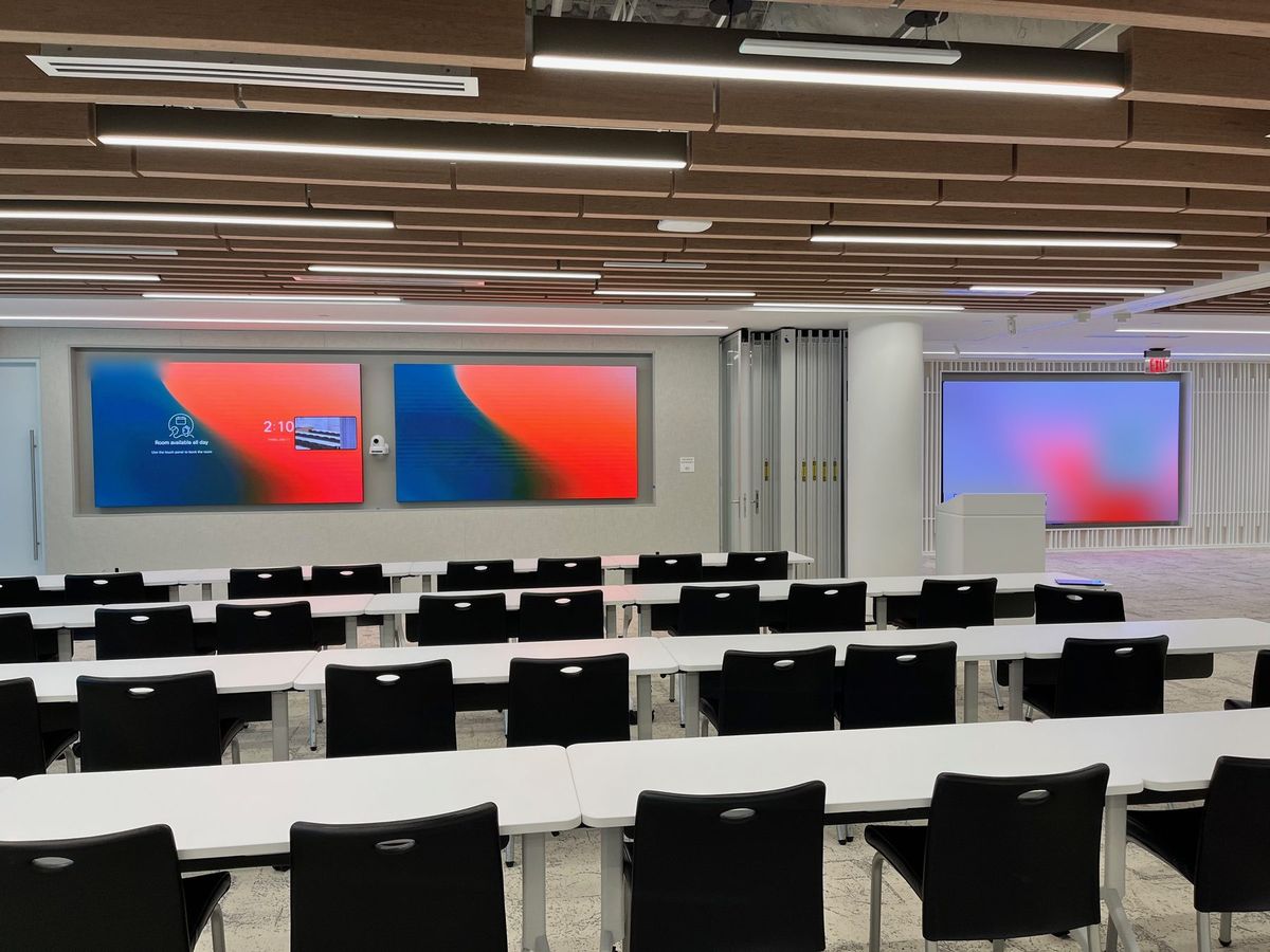 Large training room with dual LED video walls, a side display, and a presenter lectern, by Enlightened Audiovisual