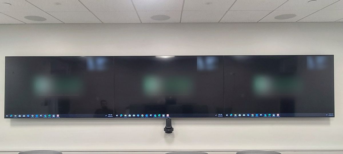 Triple-wide video conferencing display wall with a center camera in a corporate meeting room, by Enlightened Audiovisual
