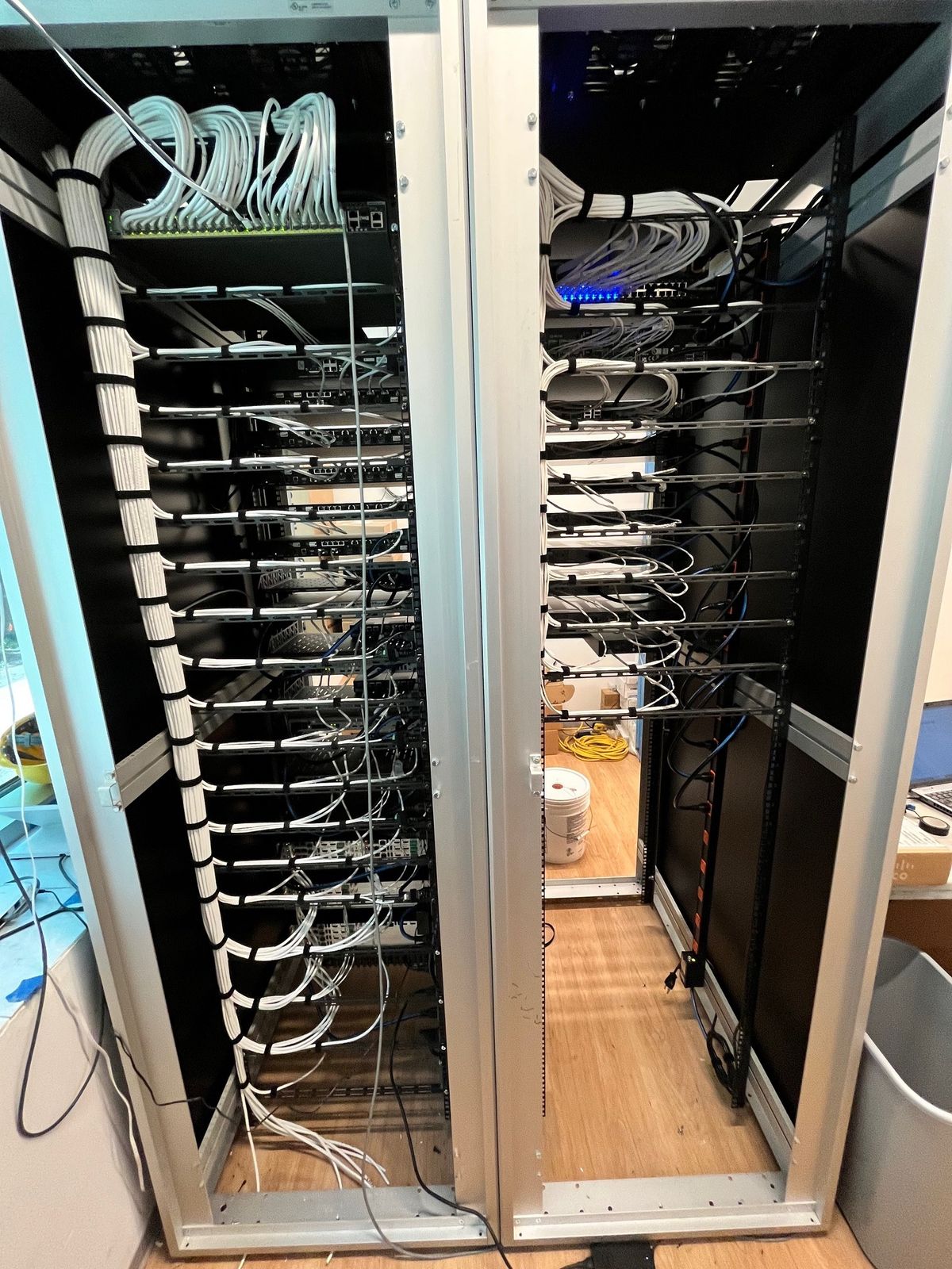Two open equipment racks mid-build with neatly dressed, bundled cabling, by Enlightened Audiovisual