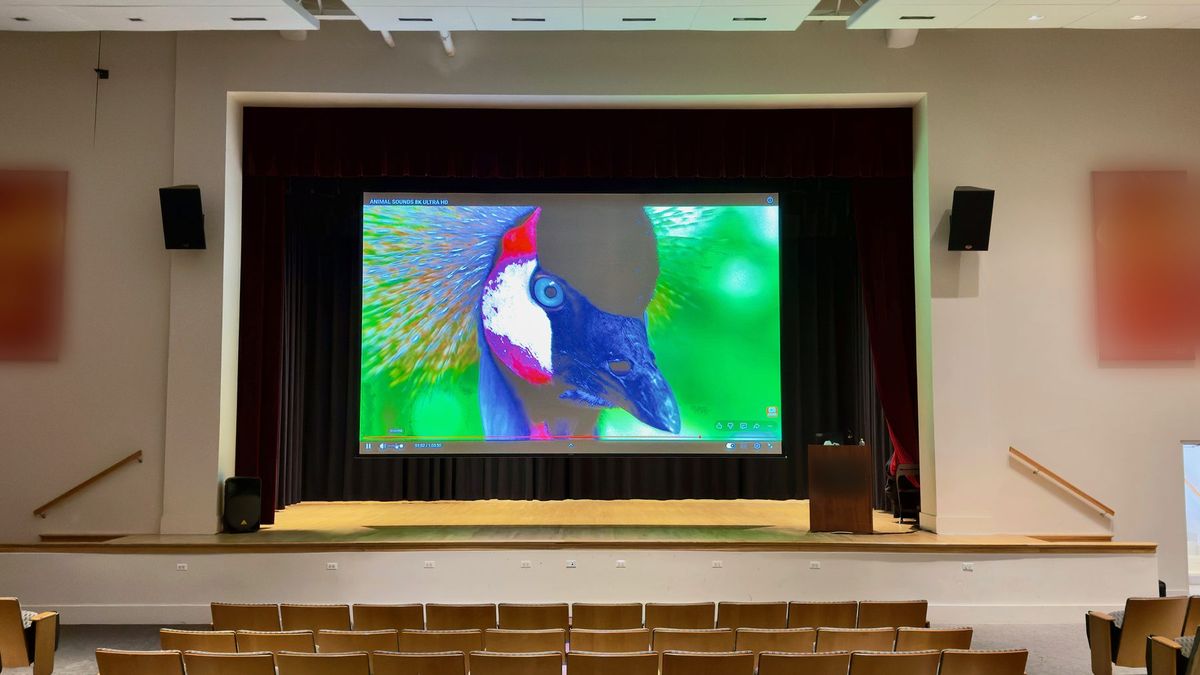 Auditorium with a large stage projection screen and stage speakers, AV integration by Enlightened Audiovisual