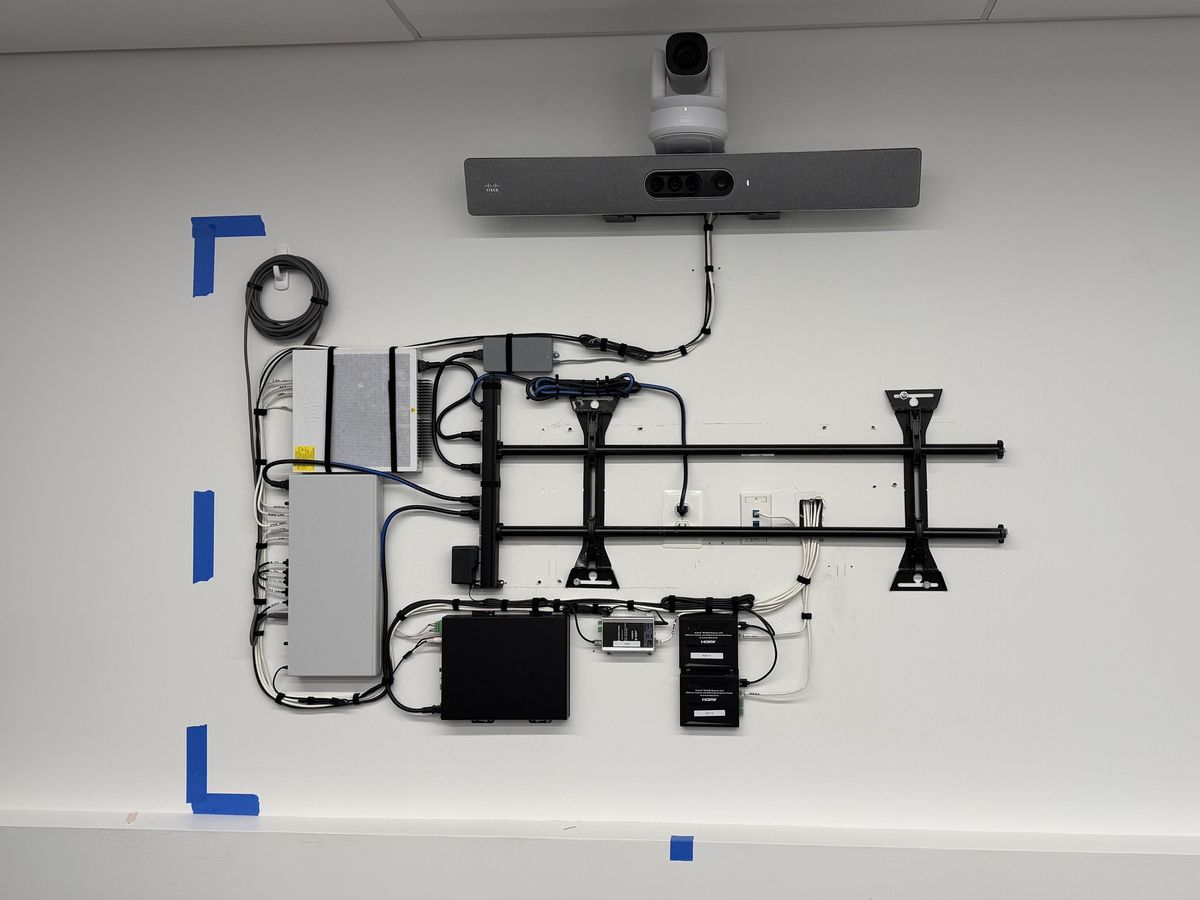 Display wall prepped with a mount, camera, video bar, and neatly dressed cabling before the display is installed, by Enlightened Audiovisual